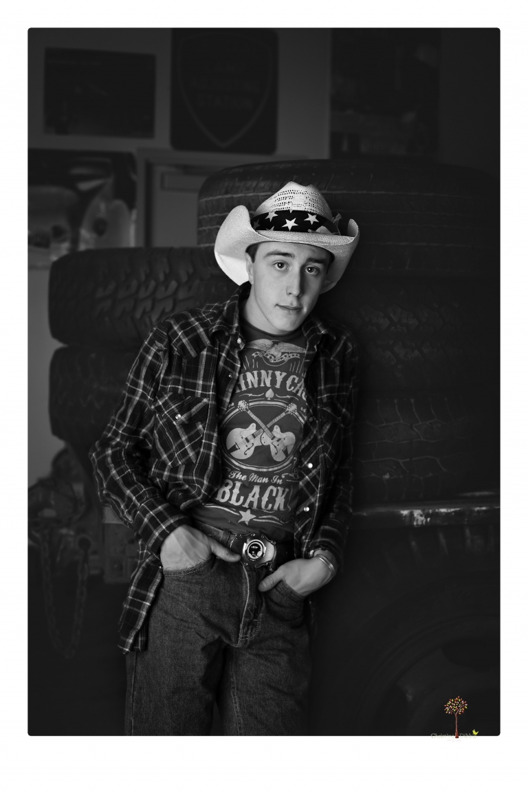 Summerville Senior Portraits taken by Christine Dibble Photography of Sonora in the auto shop with a senior boy's 1959 Jeep Willys pick-up truck and his letterman jacket.