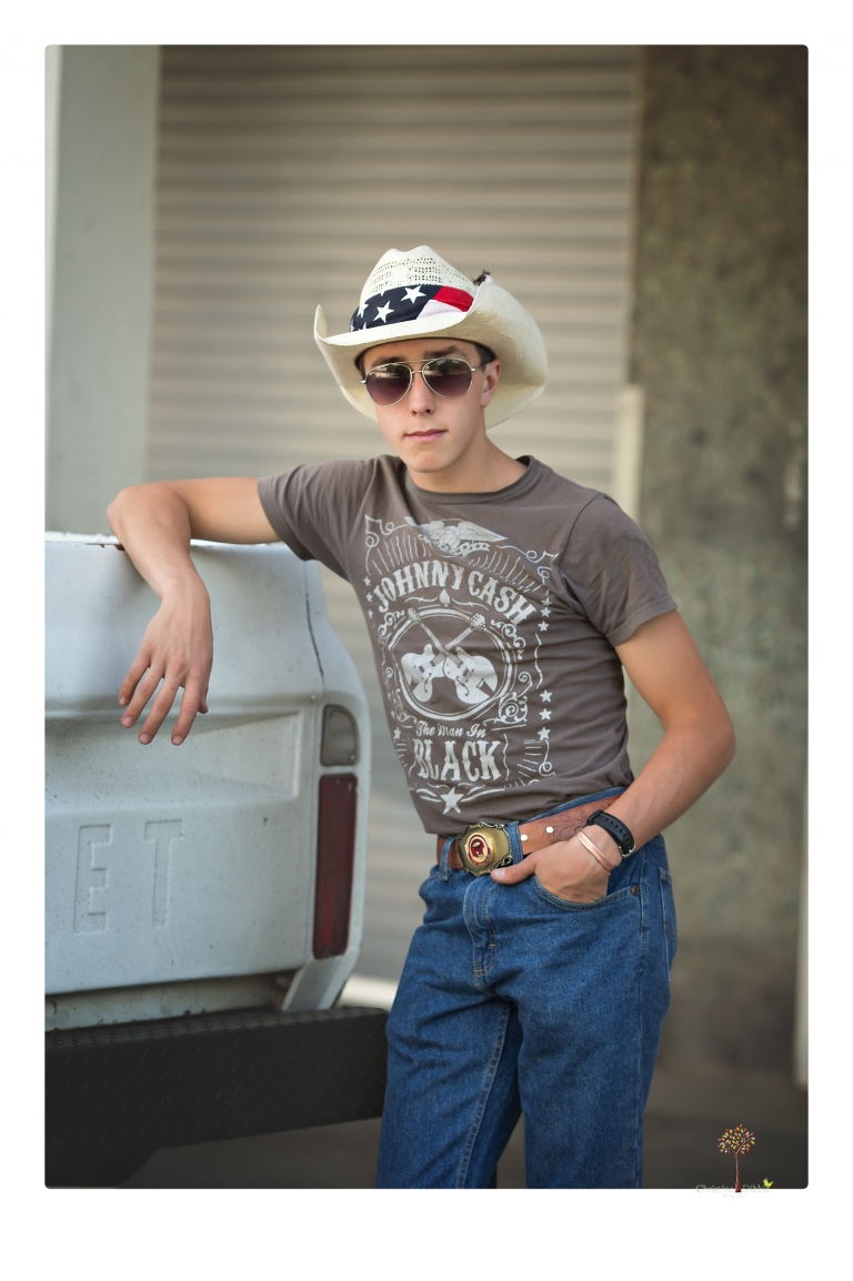 Summerville Senior Portraits taken by Christine Dibble Photography of Sonora in the auto shop with a senior boy's 1959 Jeep Willys pick-up truck and his letterman jacket.