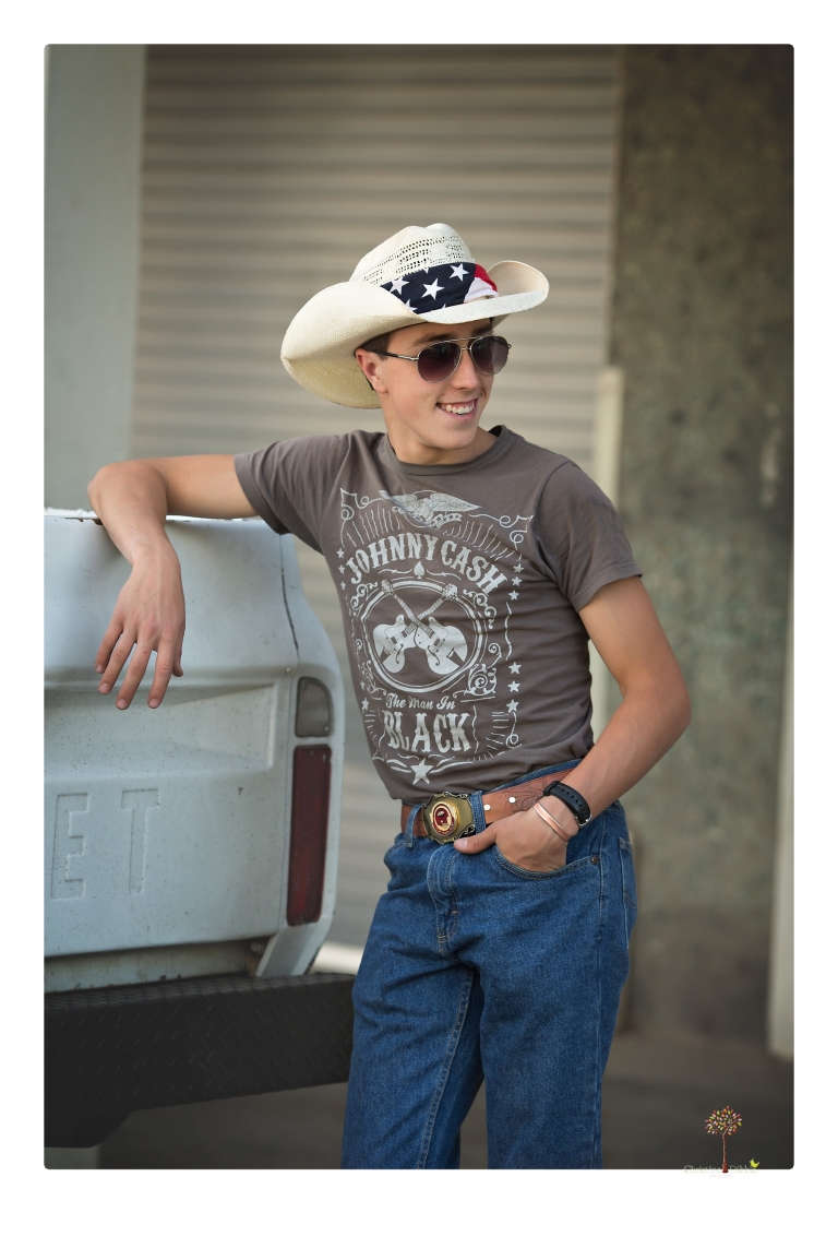 Summerville Senior Portraits taken by Christine Dibble Photography of Sonora in the auto shop with a senior boy's 1959 Jeep Willys pick-up truck and his letterman jacket.