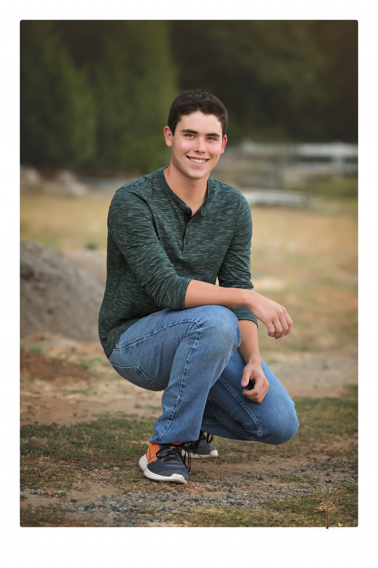 Summerville High senior portrait photographer Christine Dibble of Sonora takes senior portraits of a boy at Twain Harte Tree Farm with his trumpet, letterman jacket, and his dad's classic 1966 Chevelle.