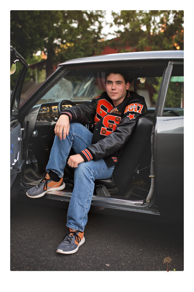 Summerville High senior portrait photographer Christine Dibble of Sonora takes senior portraits of a boy at Twain Harte Tree Farm with his trumpet, letterman jacket, and his dad's classic 1966 Chevelle.