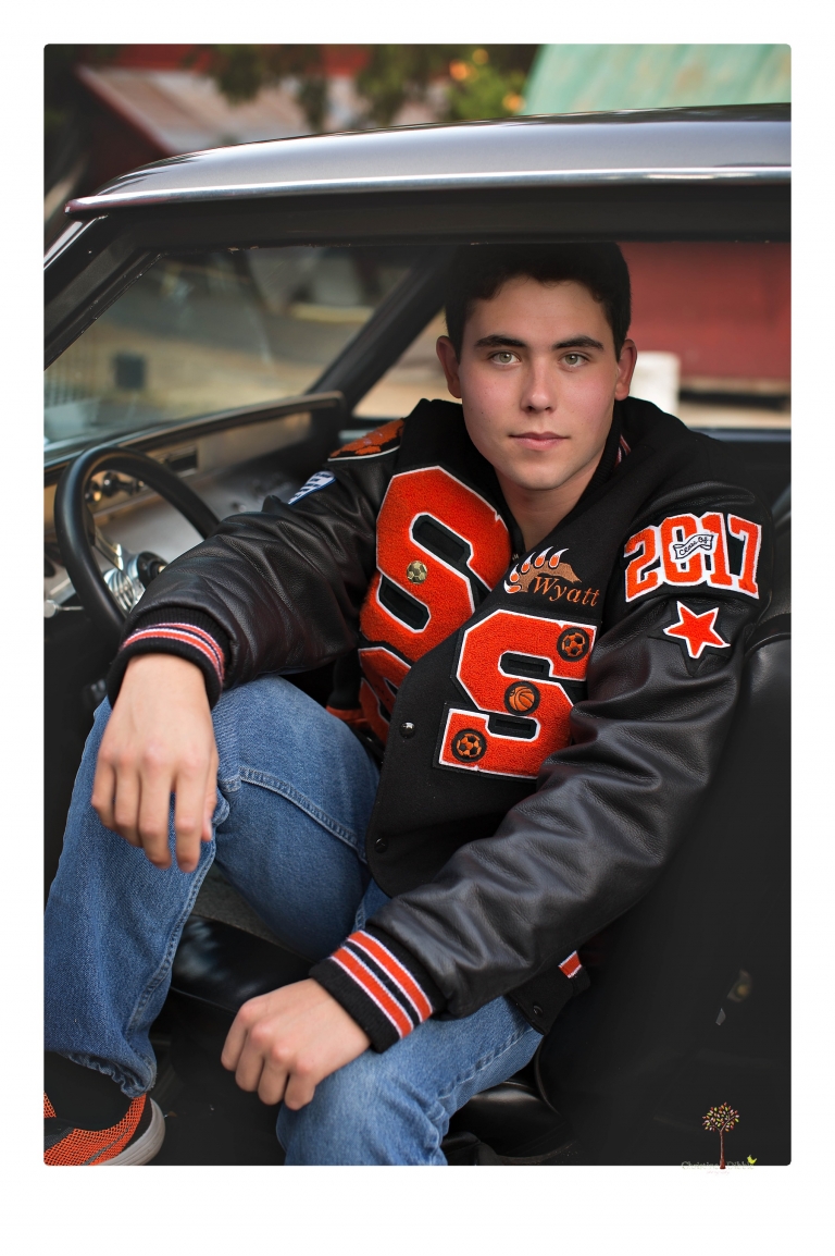 Summerville High senior portrait photographer Christine Dibble of Sonora takes senior portraits of a boy at Twain Harte Tree Farm with his trumpet, letterman jacket, and his dad's classic 1966 Chevelle.