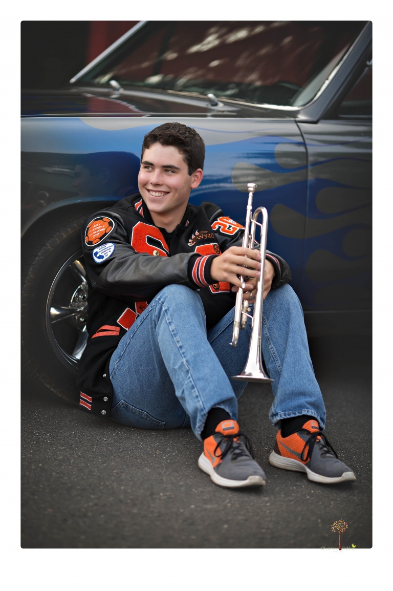 Summerville High senior portrait photographer Christine Dibble of Sonora takes senior portraits of a boy at Twain Harte Tree Farm with his trumpet, letterman jacket, and his dad's classic 1966 Chevelle.