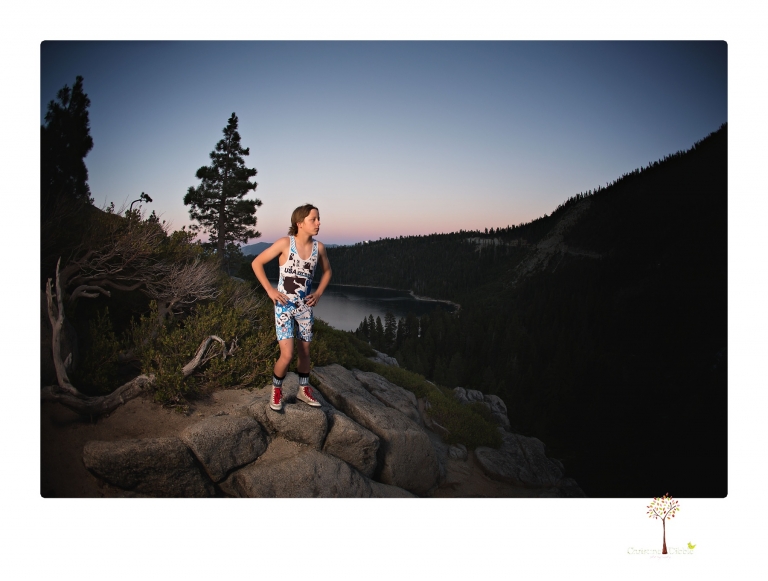 Sonora sports photographer Christine Dibble Photography takes wrestling portraits at Emerald Bay in Lake Tahoe of a wrestler on the cliffs looking over the falls and the bay at sunset with the full moon rising behind.