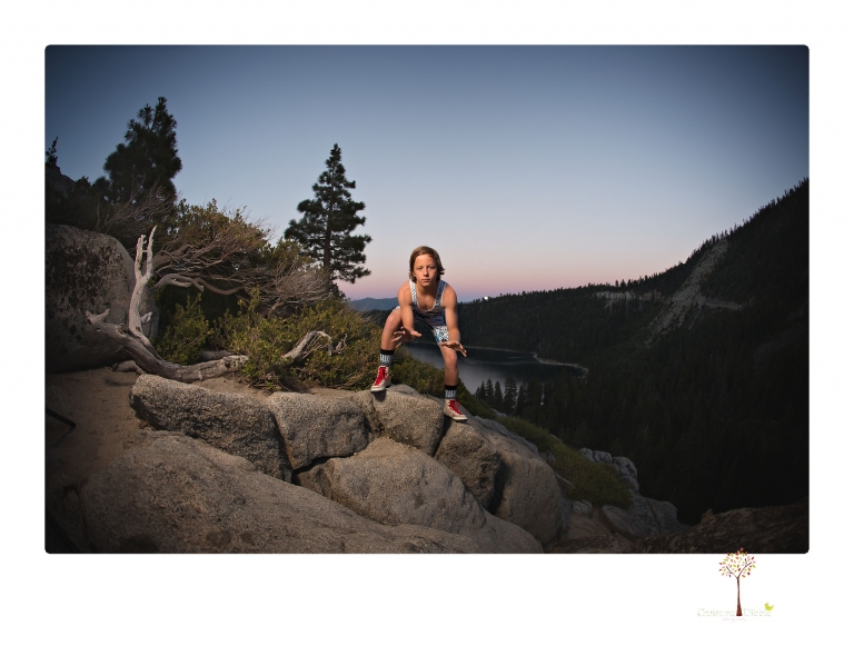 Sonora sports photographer Christine Dibble Photography takes wrestling portraits at Emerald Bay in Lake Tahoe of a wrestler on the cliffs looking over the falls and the bay at sunset with the full moon rising behind.