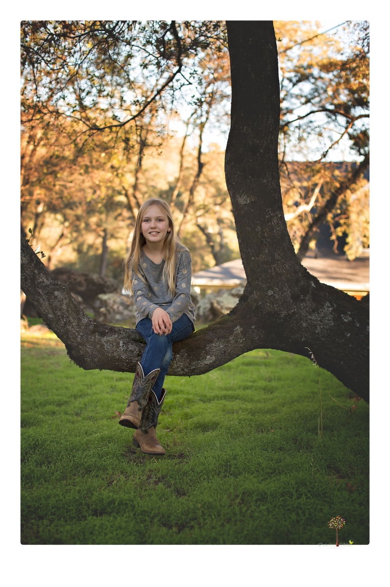 Sonora family photographer Christine Dibble Photography takes family portraits in a private vineyard as a family plays and climbs trees and rocks.