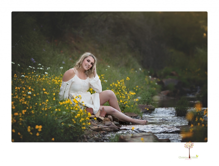 Sonora High senior portrait photographer Christine Dibble Photography takes senior portraits of a girl on her family's Chinese Camp ranch among wildflowers in a creek and with an American flag.