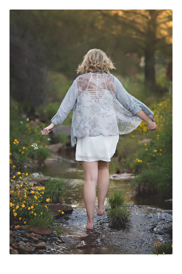 Sonora High senior portrait photographer Christine Dibble Photography takes senior portraits of a girl on her family's Chinese Camp ranch among wildflowers in a creek and with an American flag.