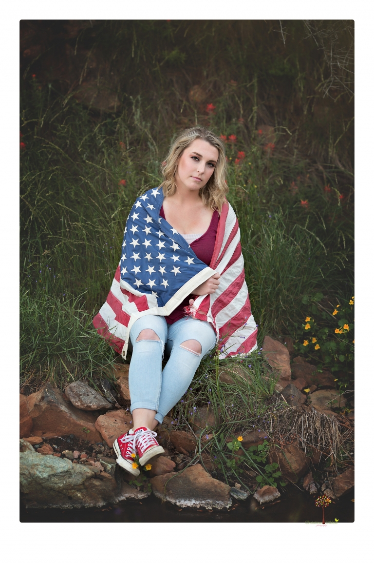 Sonora High senior portrait photographer Christine Dibble Photography takes senior portraits of a girl on her family's Chinese Camp ranch among wildflowers in a creek and with an American flag.