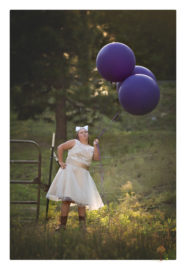 Sonora senior portrait photographer Christine Dibble Photography takes senior portraits of a girl in a lace dress with giant balloons on a velvet loveseat in a field.