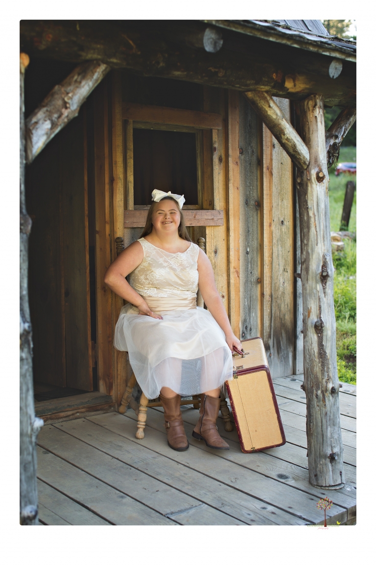 Sonora senior portrait photographer Christine Dibble Photography takes senior portraits of a girl in a lace dress with giant balloons on a velvet loveseat in a field.