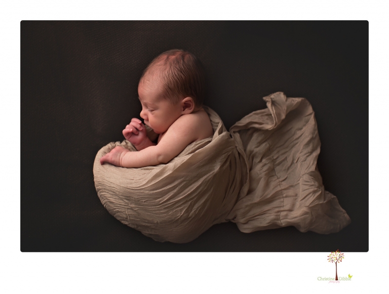 Sonora Newborn Photographer Christine Dibble Photography takes newborn portraits of a baby in a ski boot and with his parents.