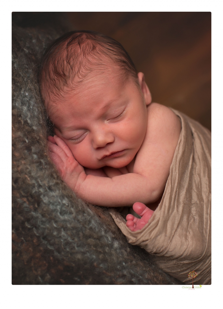 Sonora Newborn Photographer Christine Dibble Photography takes newborn portraits of a baby in a ski boot and with his parents.