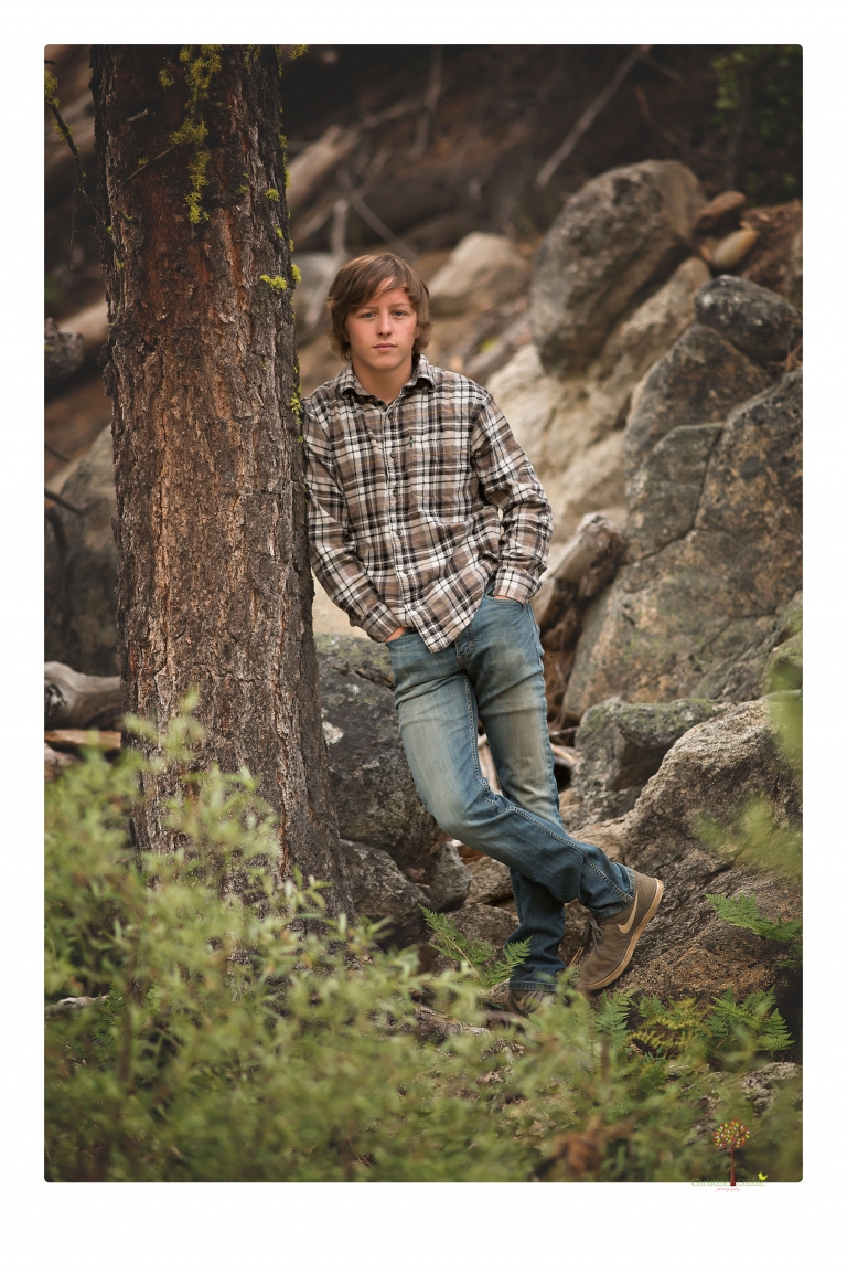 Summerville High School Senior portrait photographer Christine Dibble Photography takes four wheeling senior portraits of a boy with his trap gun, letterman jacket, and Toyota 4Runner as he drives over rocks and dives off cliffs.