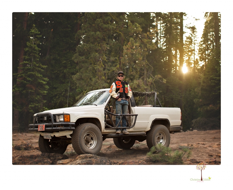 Summerville High School Senior portrait photographer Christine Dibble Photography takes four wheeling senior portraits of a boy with his trap gun, letterman jacket, and Toyota 4Runner as he drives over rocks and dives off cliffs.