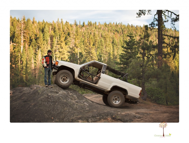 Summerville High School Senior portrait photographer Christine Dibble Photography takes four wheeling senior portraits of a boy with his trap gun, letterman jacket, and Toyota 4Runner as he drives over rocks and dives off cliffs.