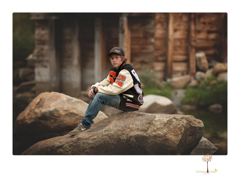 Summerville High School Senior portrait photographer Christine Dibble Photography takes four wheeling senior portraits of a boy with his trap gun, letterman jacket, and Toyota 4Runner as he drives over rocks and dives off cliffs.