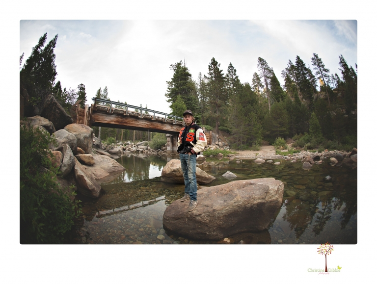 Summerville High School Senior portrait photographer Christine Dibble Photography takes four wheeling senior portraits of a boy with his trap gun, letterman jacket, and Toyota 4Runner as he drives over rocks and dives off cliffs.